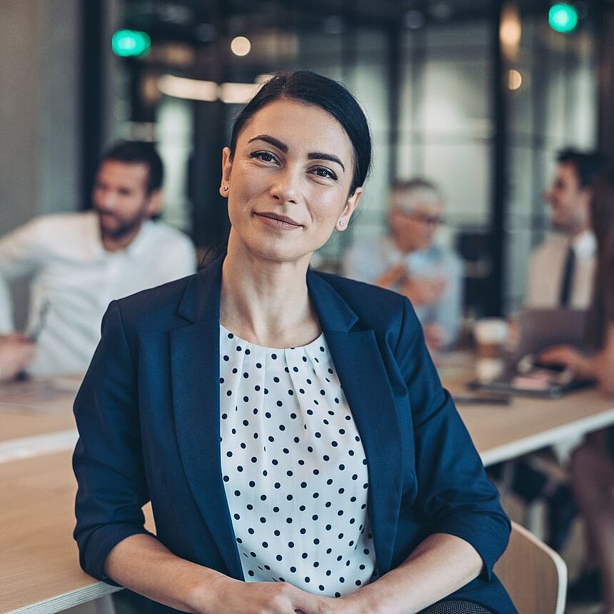 Success with vision - investing in the future of the hotel industry Self-confident businesswoman in an elegant business outfit sits in a modern meeting area looking ahead