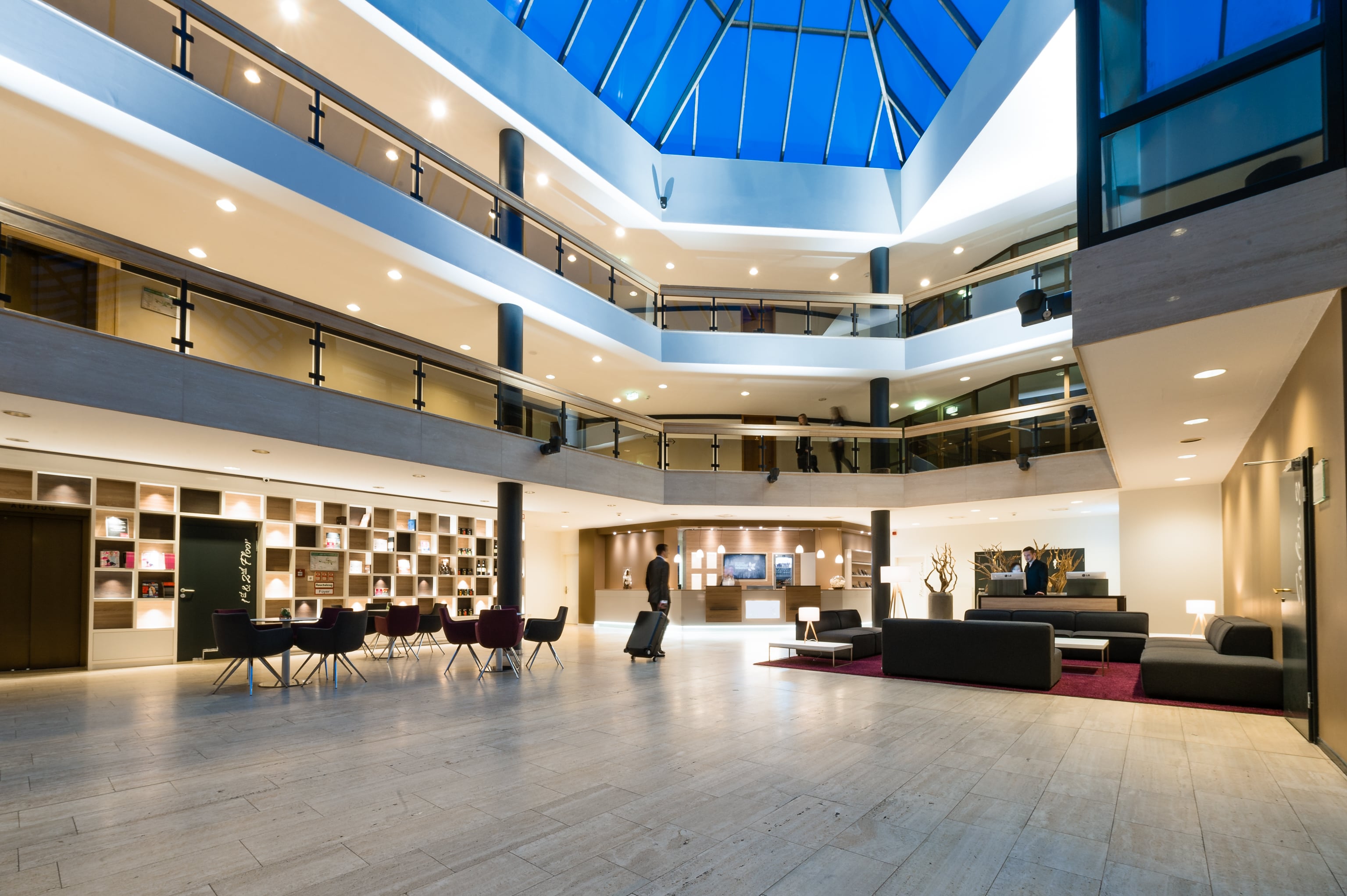 Hotel with spacious lobby area  Modern hotel with spacious lobby, stylish design and glass roof for a bright, inviting atmosphere
