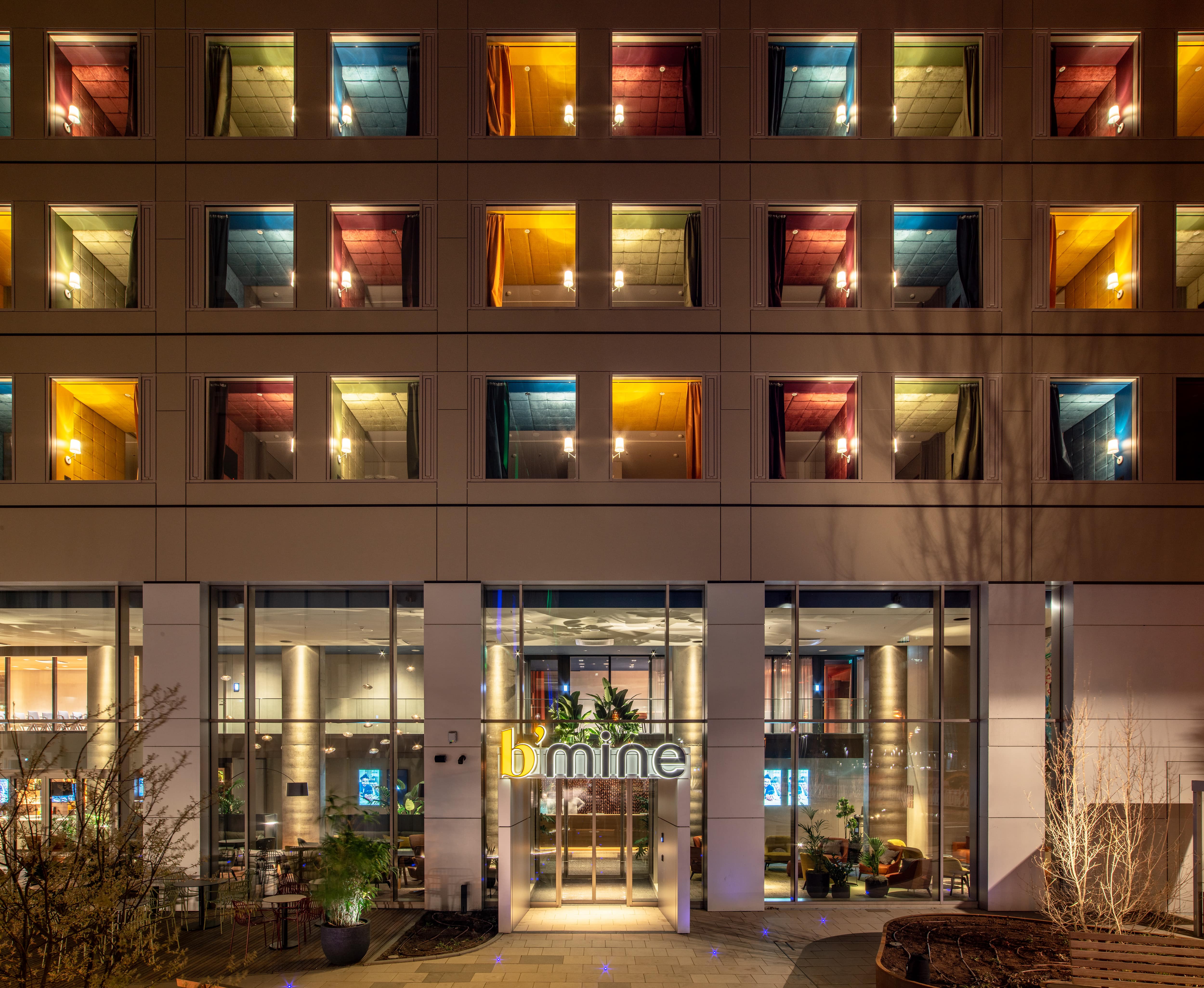 Check in & feel good - your stylish temporary home Modern hotel facade at night with warmly lit rooms and inviting entrance area