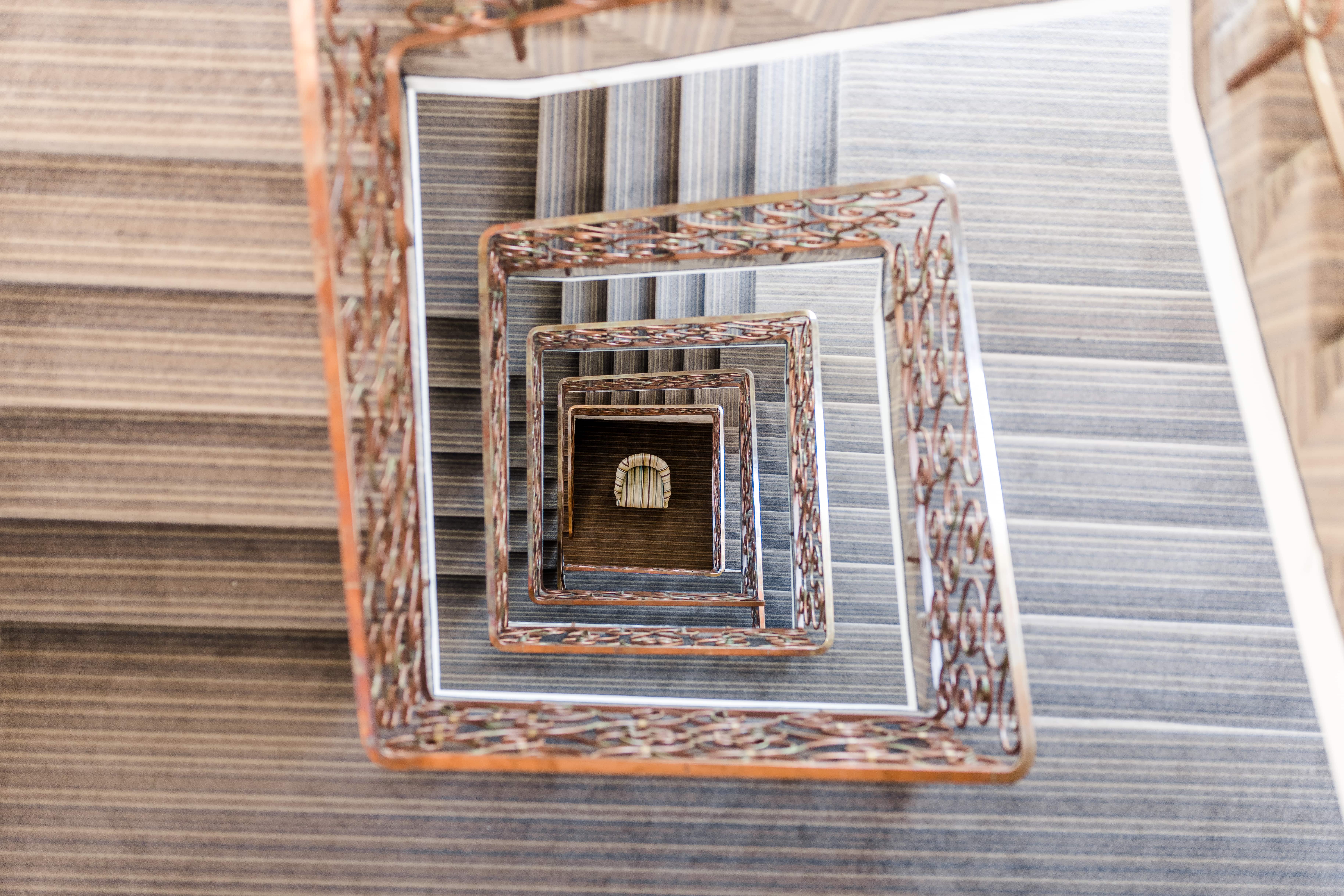 View from above into an artistically decorated staircase with recurring rectangular frames that create a fascinating depth effect. A harmonious interplay of classic details and modern design