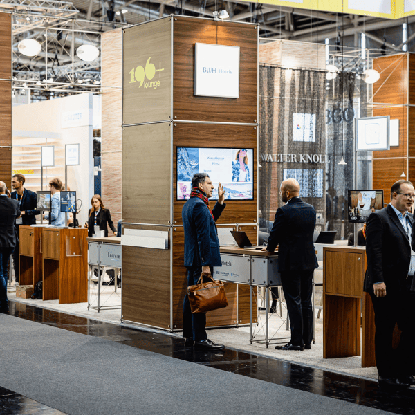 Business-Professionals beim Networking an einem Messestand auf einer Fachmesse